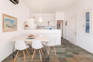 a white kitchen with a table and white chairs at Aeginia 2 in Perdika