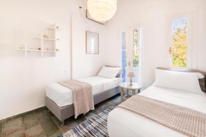 two beds in a room with white walls and windows at Aeginia 2 in Perdika