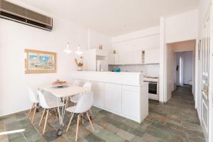a white kitchen with a white table and chairs at Aeginia 2 in Perdika
