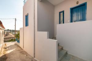 a white house with blue doors and stairs at Aeginia 2 in Perdika