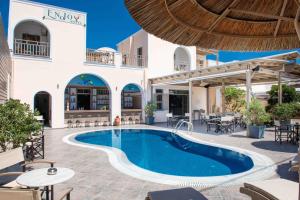 a resort with a swimming pool and tables and chairs at Enjoy Villas in Kamari