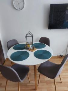 einem weißen Tisch mit vier Stühlen und einer Uhr an der Wand in der Unterkunft Stan na dan, Titanik Tuzla, centar grada in Tuzla