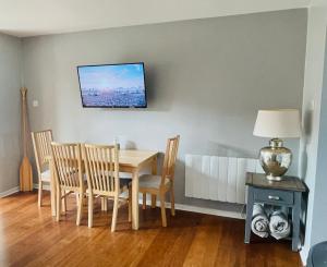 a dining room table with chairs and a tv on the wall at The Beach House, Suffolk Coast in Lowestoft