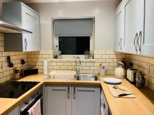 a kitchen with white cabinets and a sink at The Beach House, Suffolk Coast in Lowestoft