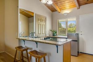 uma cozinha com um lavatório e dois bancos de bar em Castle Waimea Country Lodge em Waimea