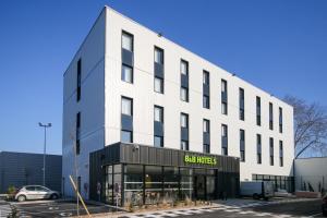 un gran edificio blanco con una tienda en un estacionamiento en B&B HOTEL Epernay en Épernay