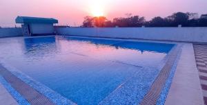 a swimming pool with the sunset in the background at Gautam Buddha Airport Hotel in Bhairāhawā