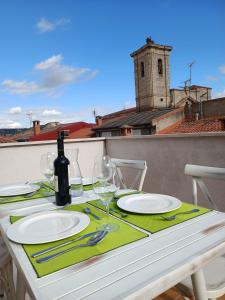 Hotel Rural Envero في Pesquera de Duero: طاولة مع أطباق وكؤوس للنبيذ على شرفة