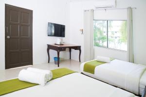 two beds in a room with a television and a desk at SANDY GARDEN RESORT LANGKAWI in Pantai Cenang