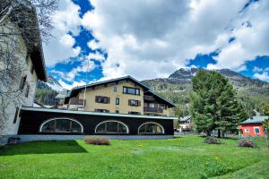 a large building with mountains in the background at Silva Appartments and Rooms in Silvaplana