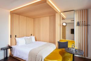 a bedroom with a white bed and a yellow chair at HOtello Schwabing in Munich