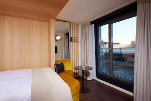a hotel room with a bed and a large window at HOtello Schwabing in Munich