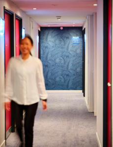 a woman walking down a hallway with a blue wall at Mercure Chartres Cathedrale in Chartres