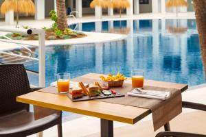 a table with food and drinks next to a pool at Hotel Cabogata Jardín in Retamar