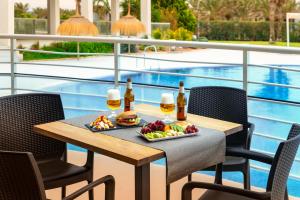 a table with a tray of food and two glasses of beer at Hotel Cabogata Jardín in Retamar