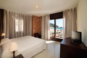 a bedroom with a bed and a television and a window at Hotel Capri in Tossa de Mar