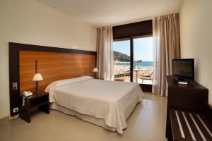 a bedroom with a bed and a television and a balcony at Hotel Capri in Tossa de Mar