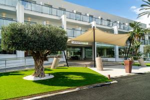 a tree in front of a building with a tent at Hotel Cabogata Jardín in Retamar