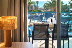 a room with a table and chairs and a balcony at Hotel Cabogata Jardín in Retamar