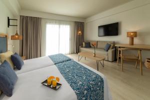 a hotel room with a large bed and a living room at Hotel Cabogata Jardín in Retamar
