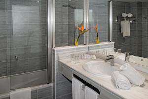 a bathroom with a sink, mirror, and bath tub at Hotel Cabogata Jardín in Retamar