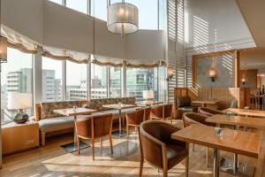 a restaurant with tables and chairs and large windows at Grand Hyatt Erawan Bangkok in Bangkok
