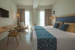 a hotel room with a large bed and a desk at Hotel Cabogata Jardín in Retamar