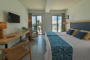 a hotel room with a bed and a desk and a television at Hotel Cabogata Jardín in Retamar