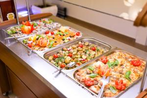 a buffet line with several trays of pizza and vegetables at Alean Family Resort & SPA Sputnik 4* Ultra All Inclusive in Sochi