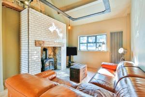 a living room with a leather couch and a fireplace at Dunromin Cottage, Hot Tub & Garden in Coxhoe