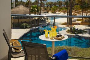 a table with drinks on it next to a pool at Hotel Cabogata Jardín in Retamar