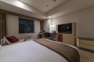 a hotel room with a bed and a flat screen tv at JR Kyushu Hotel Blossom Hakata Central in Fukuoka