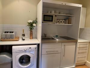 a kitchen with a washing machine and a microwave at Southernwood - West Wing in Didcot