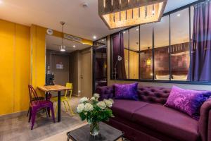 パリにあるBE YOU LUXURY APART'HÔTEL Parisの紫色のソファとテーブル付きのリビングルーム