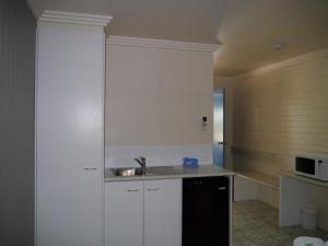 a kitchen with white cabinets and a sink at Emu Park Motel in Emu Park