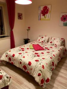 a bed with a white comforter with red flowers on it at Voie Verte in Cornimont