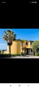 een gebouw met twee palmbomen en een fiets geparkeerd aan de voorkant bij Mare Nostrum Casa Vacanza in Licata