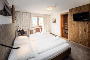 a hotel room with two beds and a television at Hotel Alpenfeuer Montafon in Sankt Gallenkirch