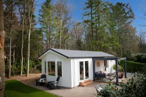 een kleine witte schuur met een patio in een tuin bij StayatSas Tiny House Sam in de bossen op de Veluwe! in Epe