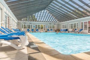 une grande piscine avec des chaises bleues dans un bâtiment dans l'établissement Résidence Pierre & Vacances Les Jardins de la Côte d'Opale, à Le Touquet-Paris-Plage
