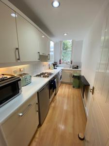 a kitchen with white appliances and a wooden floor at Magdala Apartment in Nottingham