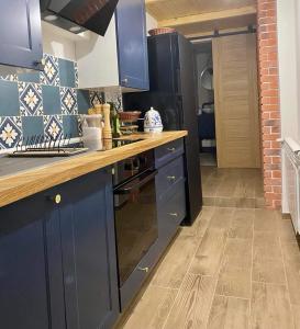 a kitchen with blue cabinets and a wooden counter top at BRICK Apartment in Žilina