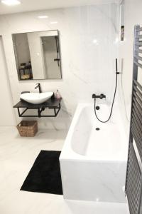 ein weißes Badezimmer mit einem Waschbecken und einem Spiegel in der Unterkunft Krásny priestranný slnečný apartmán v centre mesta in Trenčín