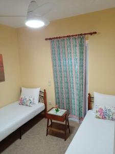 een kamer met 2 bedden, een tafel en een raam bij Alexandra's Apartment in Kalamitsi