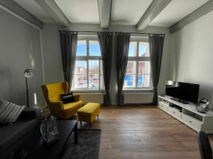 - un salon avec un canapé et un fauteuil jaune dans l'établissement Ferienwohnung Hafensicht 25507, à Weener