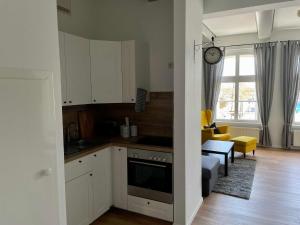 a kitchen with white cabinets and a living room at Ferienwohnung Hafensicht 25507 in Weener