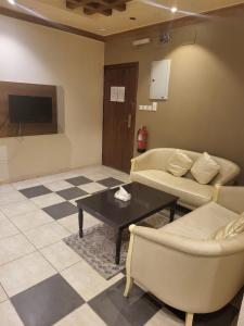 a living room with couches and a table and a tv at Safwt Aldyar Furnished Units in Abha