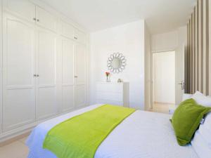 a white bedroom with a green blanket on a bed at Mahostly Apartamento Comillas SC in Arrecife
