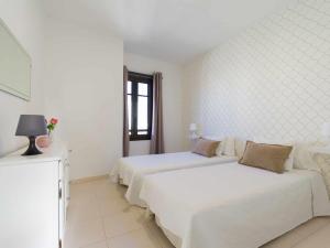 1 dormitorio blanco con 2 camas y ventana en Mahostly Apartamento Comillas SC, en Arrecife