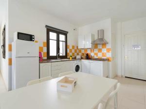 a white kitchen with a table and a white refrigerator at Mahostly Apartamento Comillas SC in Arrecife